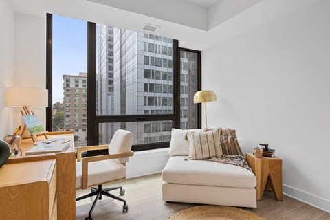 a living room with a large window and a couch and a desk with a chair